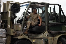 A service member reverses in a forklift while moving cargo.
