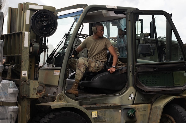 A service member reverses in a forklift while moving cargo.