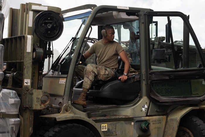 A service member reverses in a forklift while moving cargo.