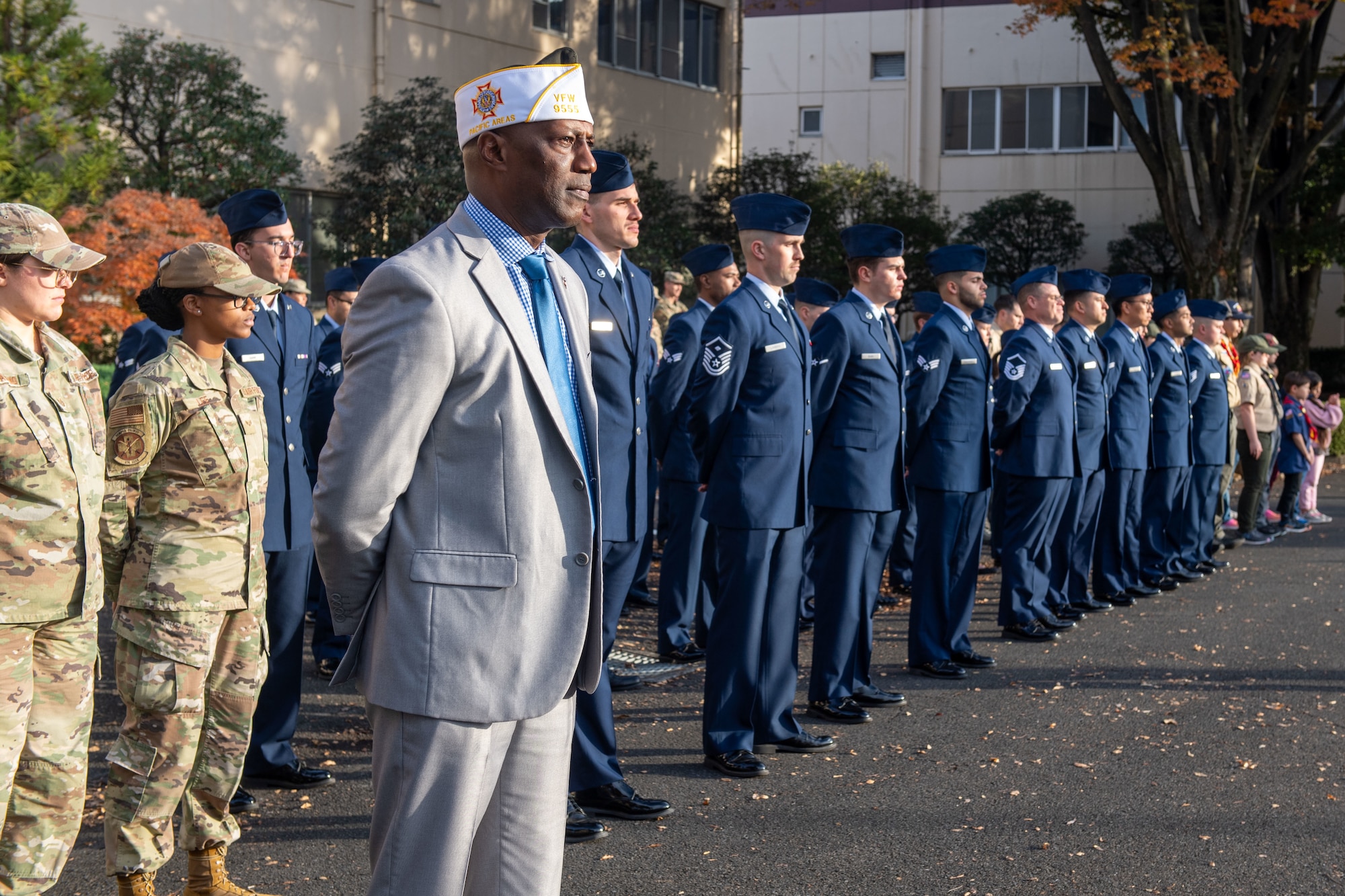 Military and community members stand at parade rest.