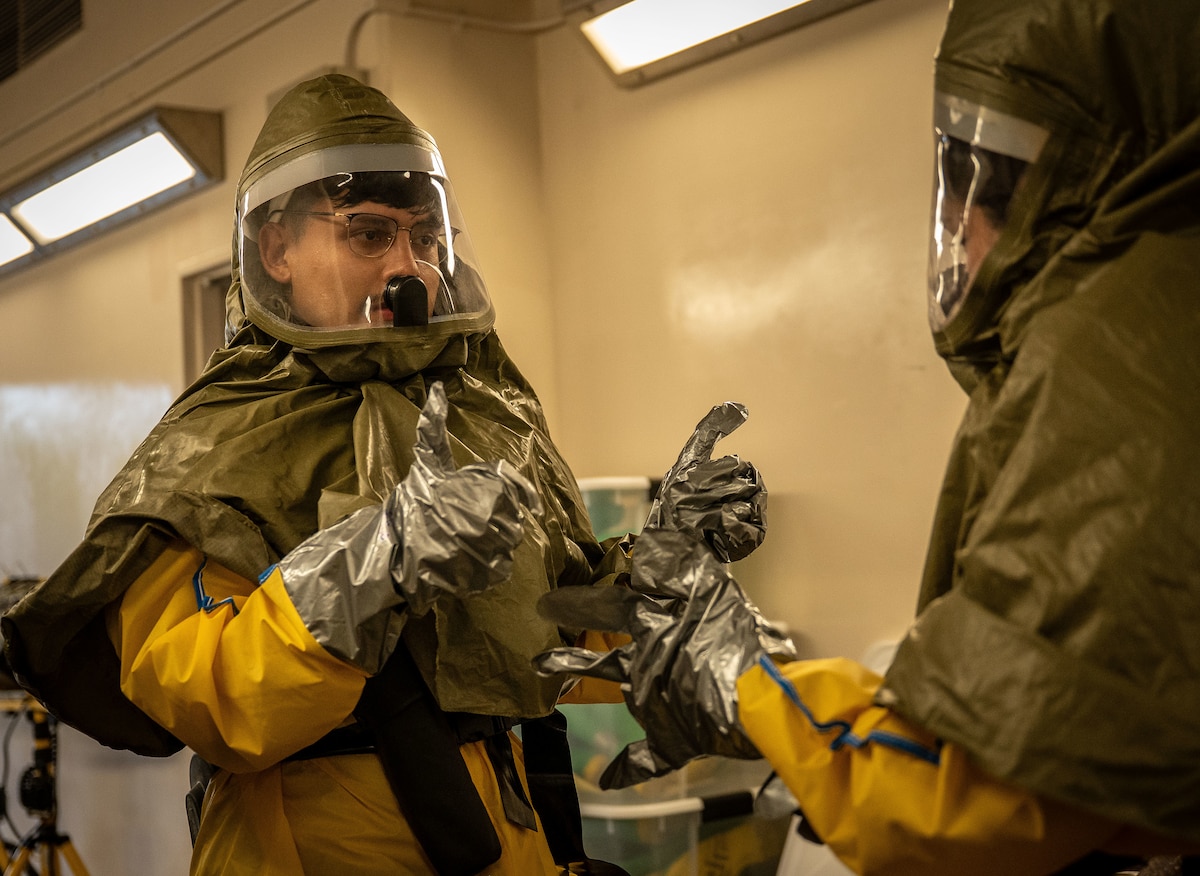 Airmen check each other's equipment.