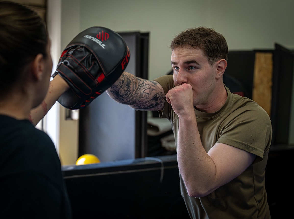An Airman punches a boxing glove for training.
