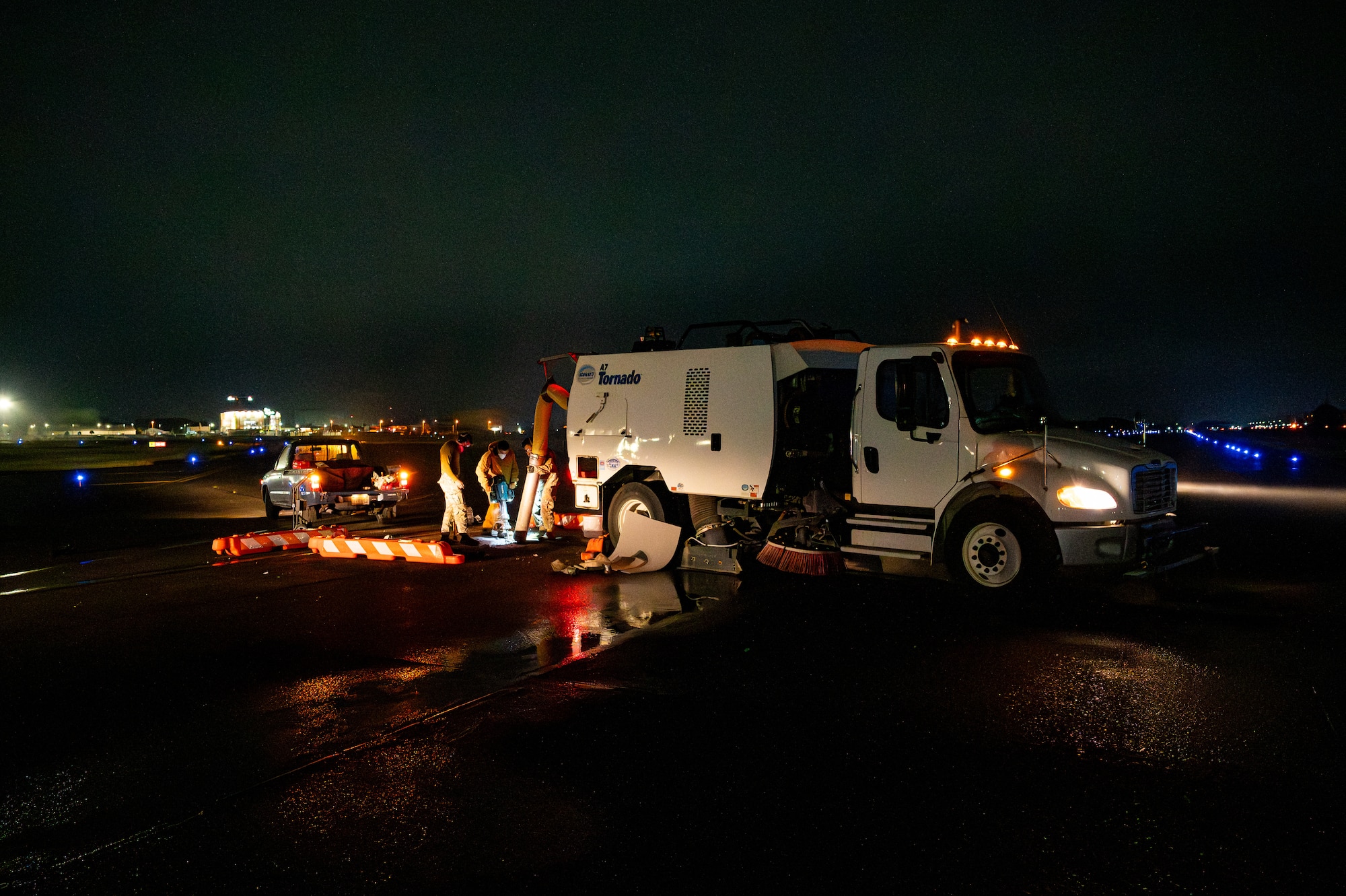 Military members pour concrete out of a truck.