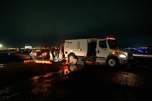 Military members pour concrete out of a truck.
