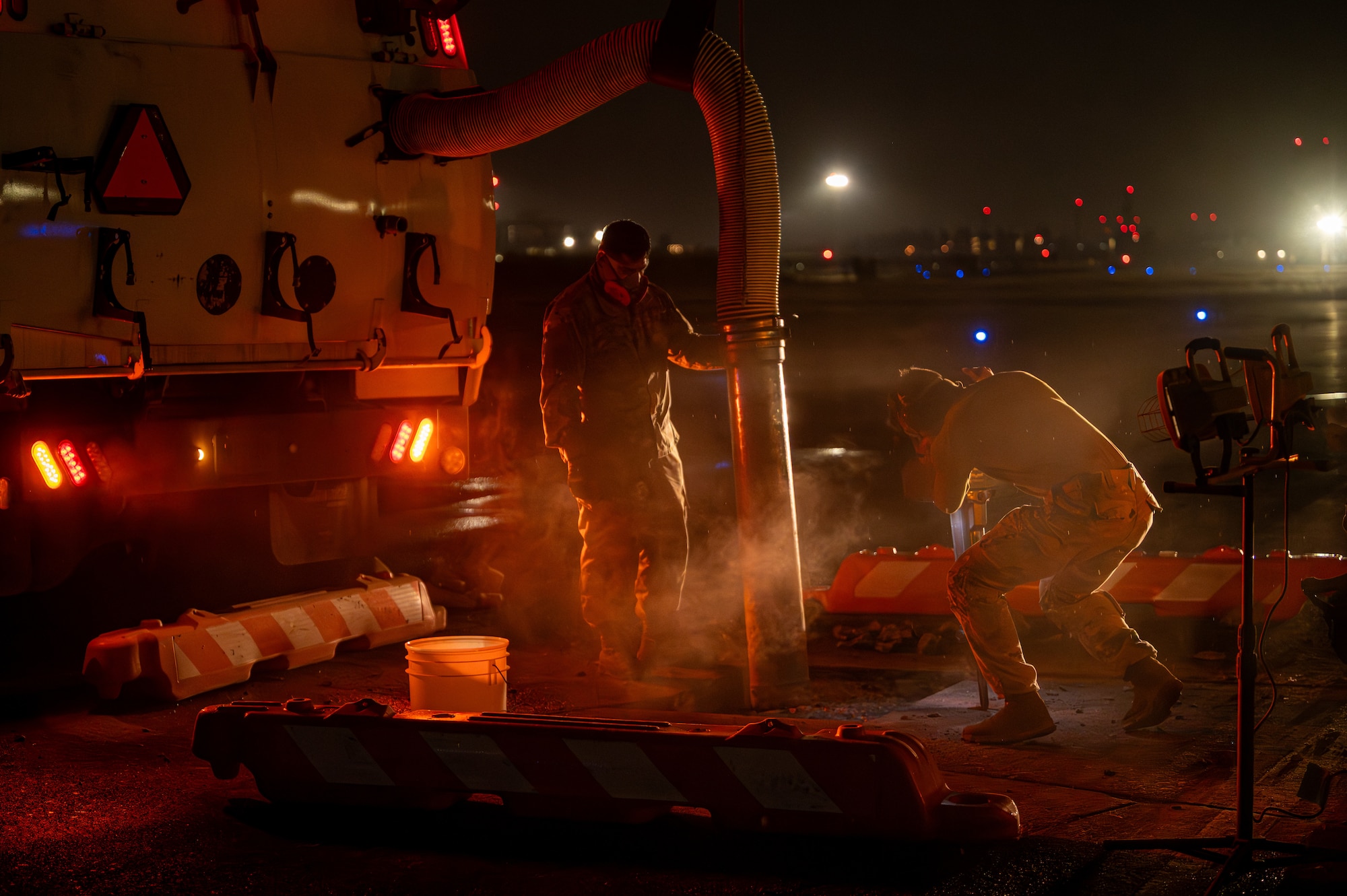 Two airmen conduct rapid airfield damage repair at night.