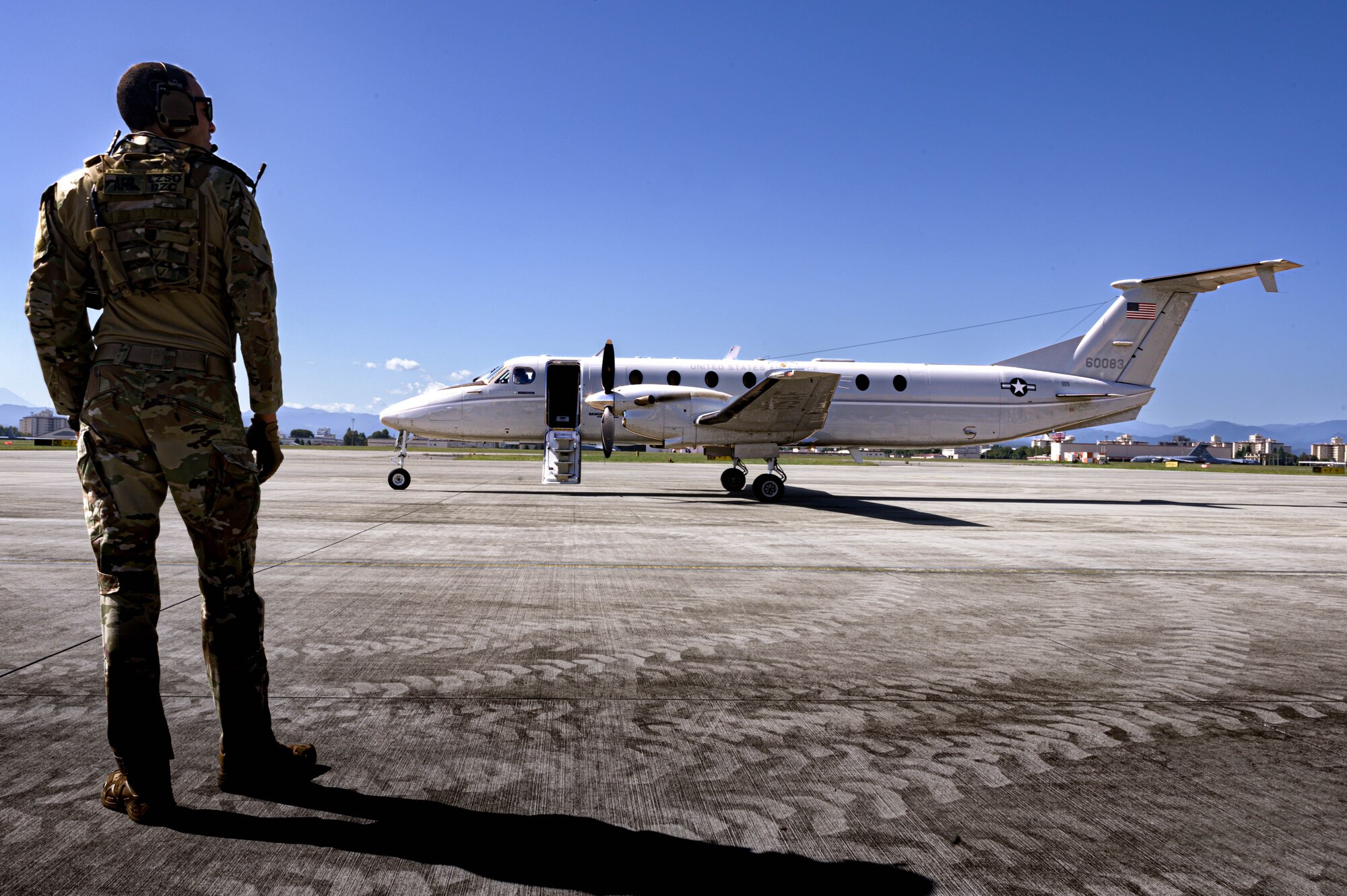 A military member inspects the area surrounding a C-12 aircraft.