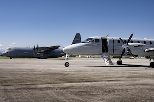 A C-12J aircraft and a C-130J aircraft are parked next to each other.