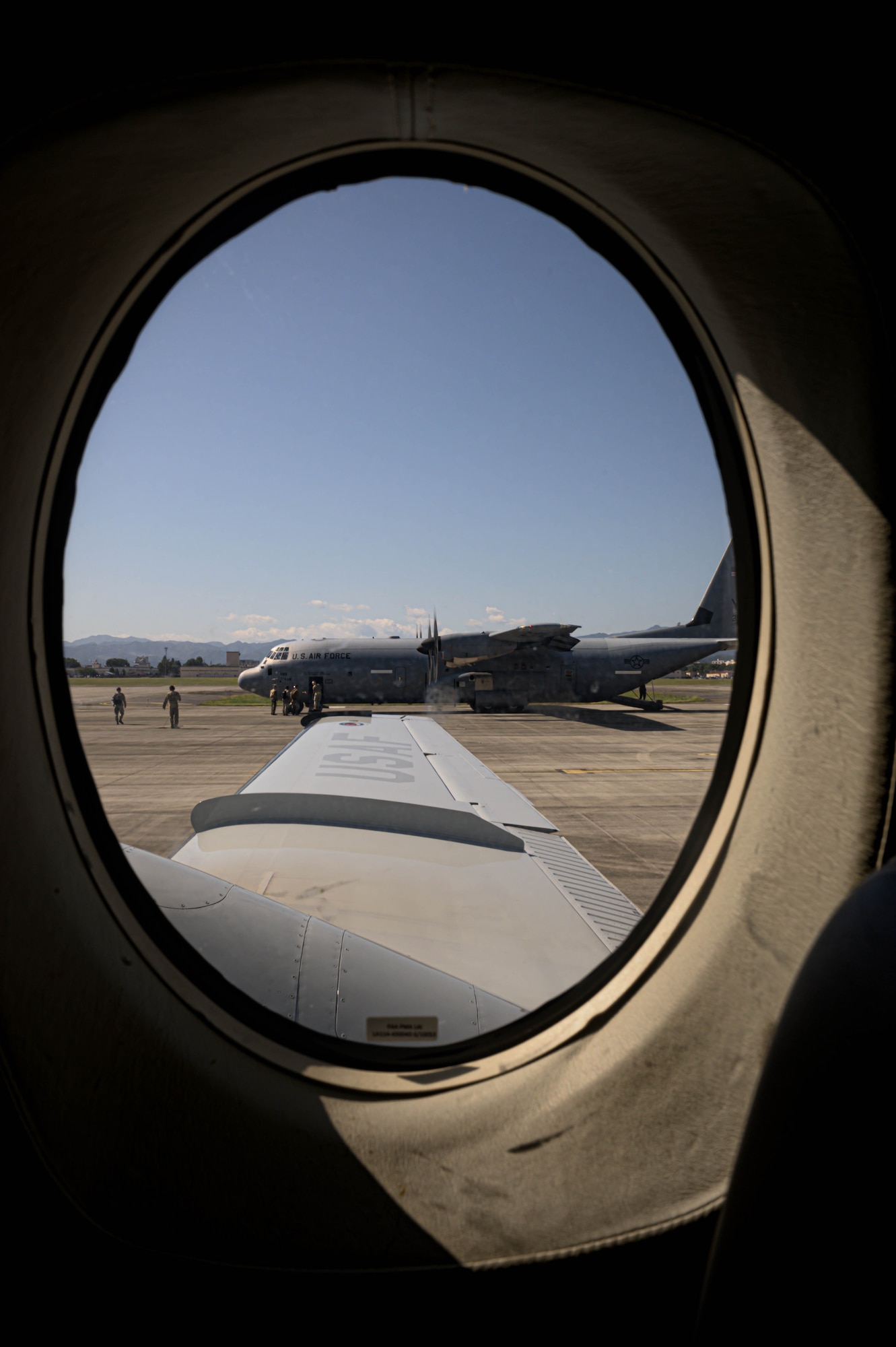 A C-130J aircraft is parked next to a C-12 aircraft.