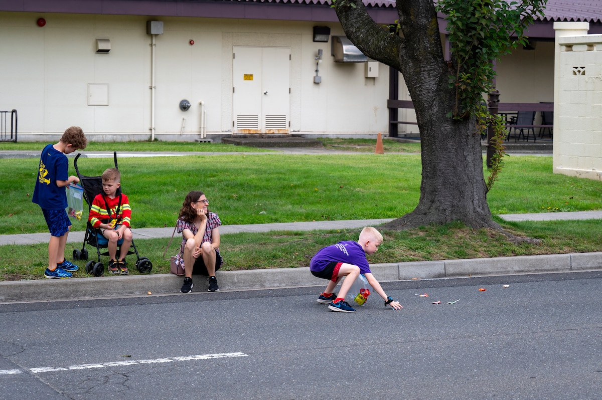 A child collects candy during a Fire Prevention Week parade at Misawa Air Base, Japan, Oct. 5, 2025. Fire Prevention Week fosters the skills and awareness necessary to prevent incidents, protect the base community, and keeps the 35th Fighter Wing mission-ready. (U.S. Air Force photo by Senior Airman Brittany Russell)