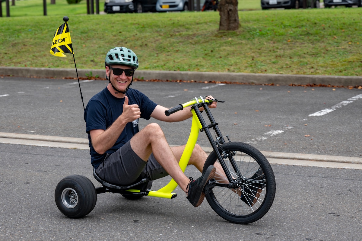 A Fire Prevention Week parade participant smiles for a photo while riding a tricycle at Misawa Air Base, Japan, Oct. 5, 2025. Through education and outreach, these efforts support the protection of personnel and resources, directly contributing to the 35th Fighter Wing’s ability to accomplish its mission. (U.S. Air Force photo by Senior Airman Brittany Russell)