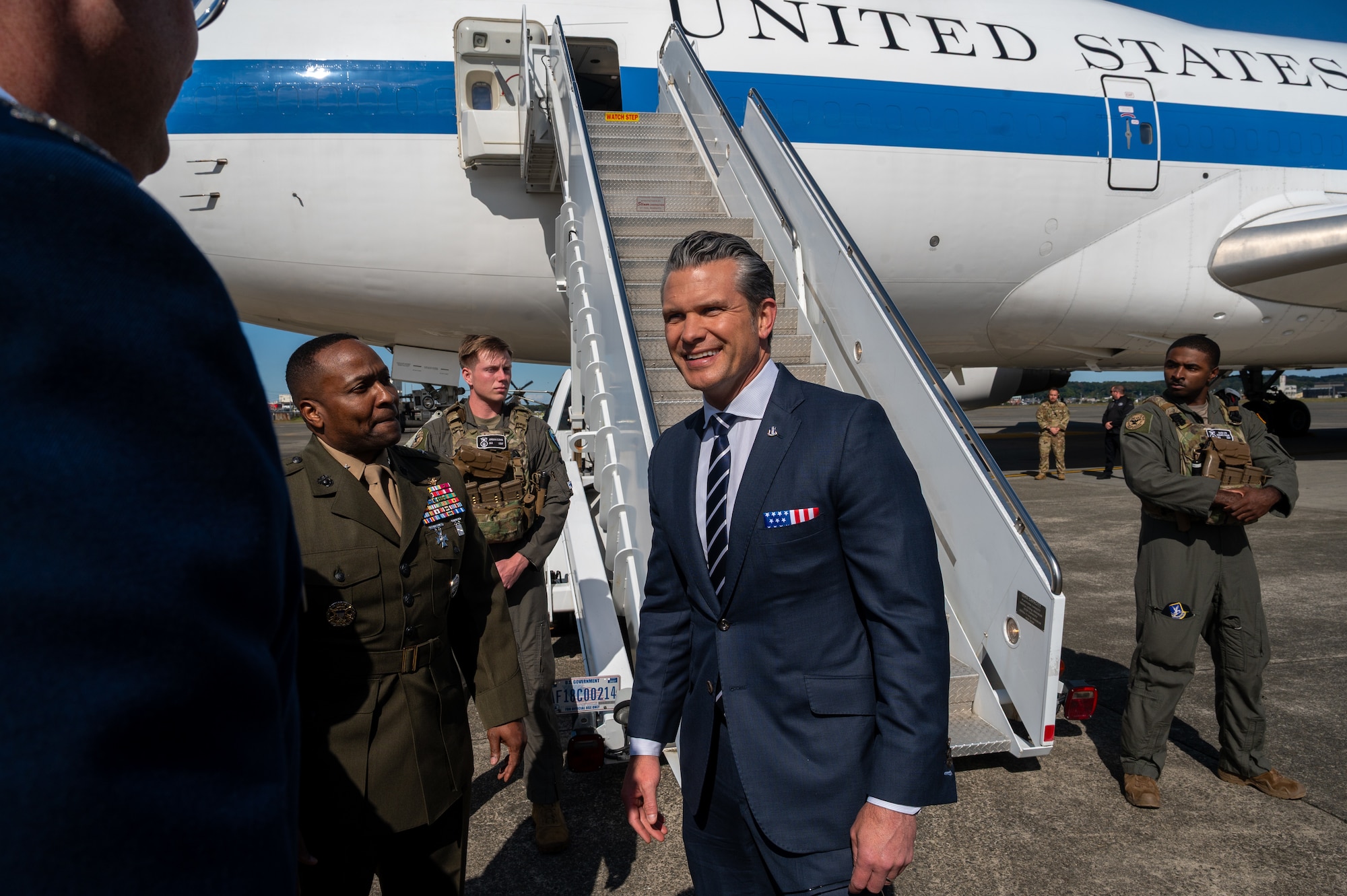 U.S. Secretary of War Pete Hegseth smiles as he meets U.S. service members after exiting an aircraft.