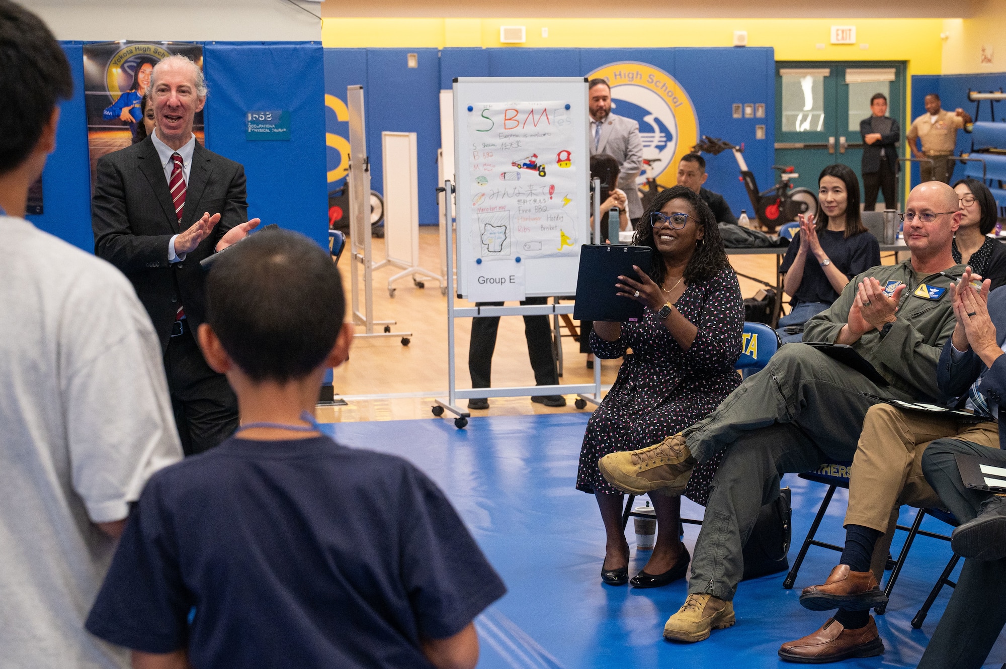 An audience claps for two presenters.