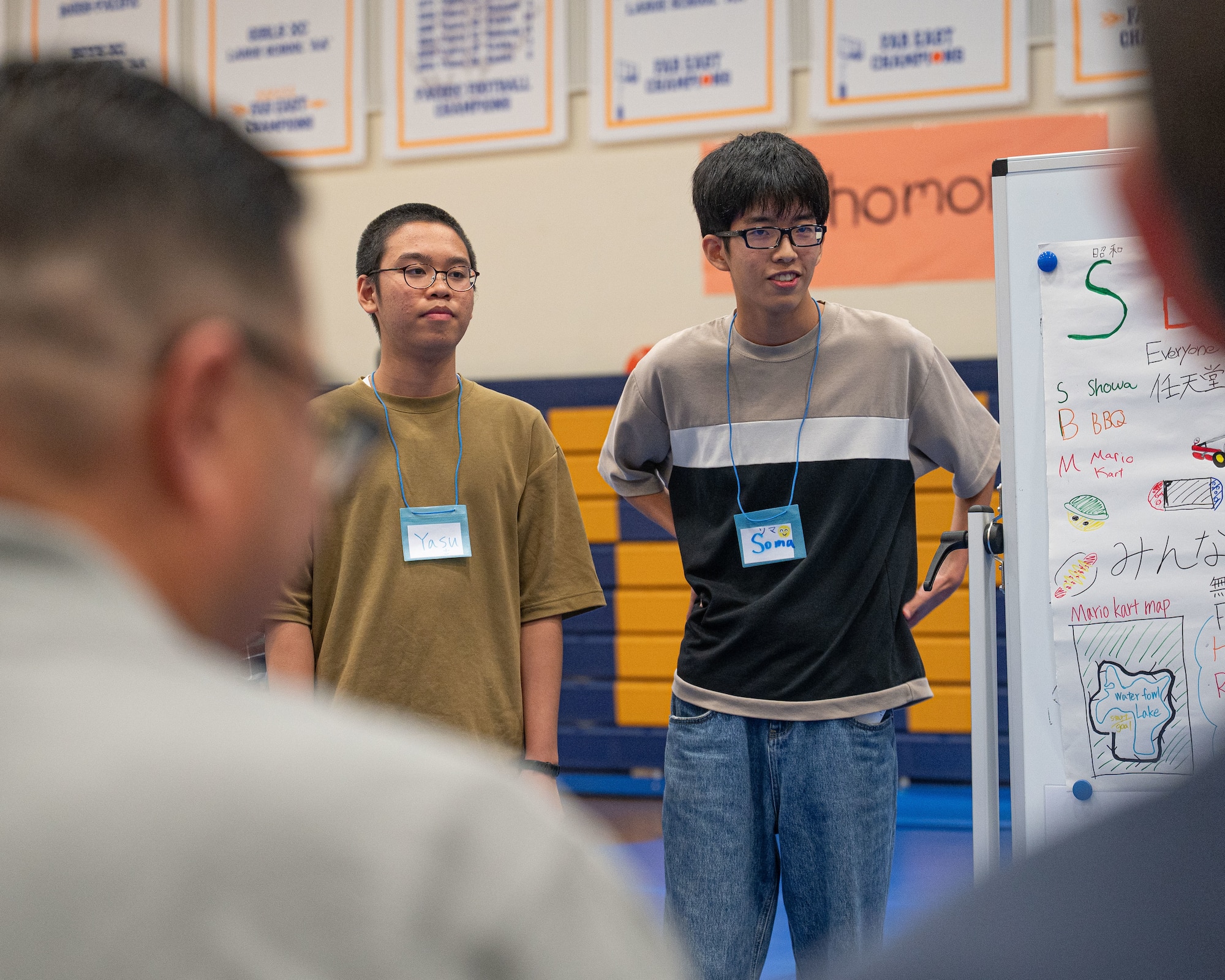 Two children stand next to each other in a gymnasium.