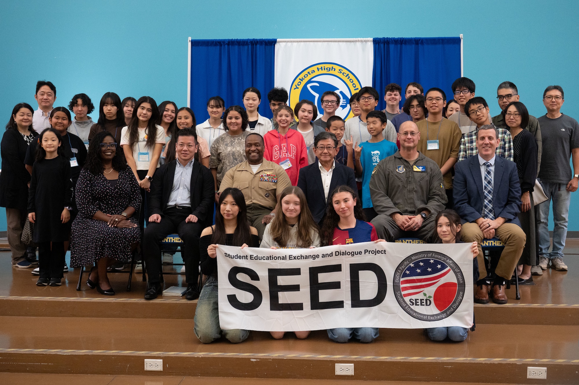 People sit on the stage and smile for a group photo