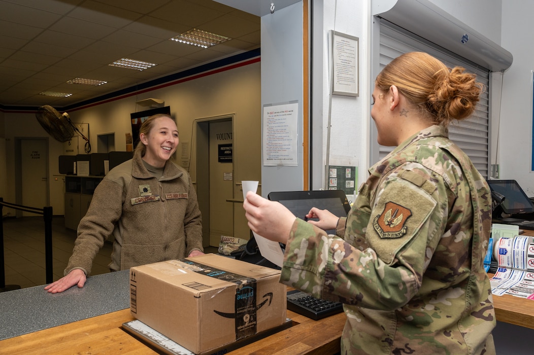 Airman 1st Class Kaylee Moss, 786th Force Support Squadron postal clerk, receives outbound mail for U.S. Air Force Lt. Col. Connie Converse, 86th Healthcare Operations Squadron commander, at the Northside Post Office on Ramstein Air Base, Germany, Nov. 7, 2025.