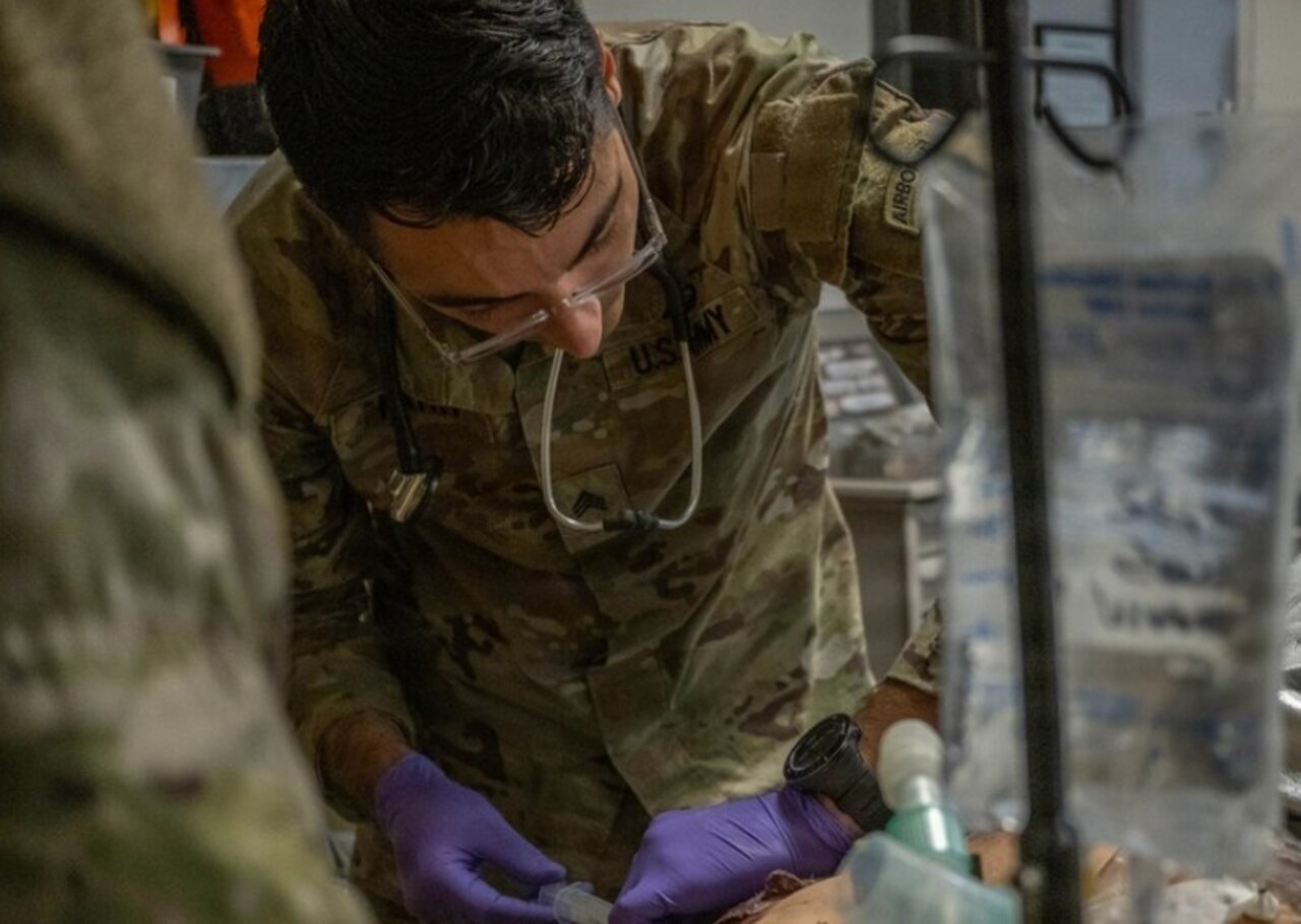 A soldier provides simulated medical care to a mannequin.