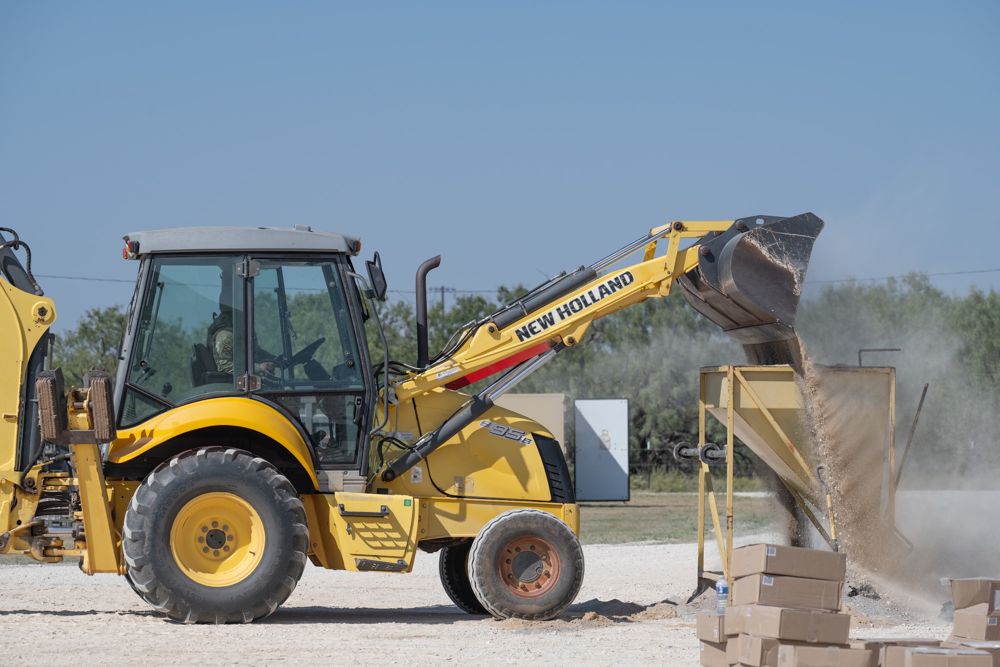 A U.S. Airman assigned to the 7th Civil Engineer Squadron operates a New Holland B95B backhoe loader during exercise Coyote Shield at Dyess Air Force Base, Texas, Oct. 16, 2025. Airmen from the 7th CES and 7th Security Forces Squadron gained experience in recovering base operations, receiving support forces, and re-establishing command and control, increasing the 7th Bomb Wing's readiness to respond in degraded conditions.  (U.S. Air Force photo by Airman 1st Class Caleb Schellenberg)