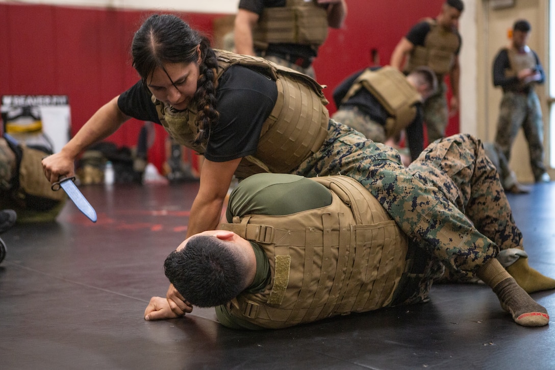 U.S. Marine Corps Staff Sgt. Karyme Camargo, a Martial Arts Instructor and a transmissions chief, conducts knife techniques on Gunnery Sgt. Jesus Cervantes, a MAI and a basic aircraft maintenance Marine, during the Marine Corps Martial Arts 25th anniversary symposium hosted by the Martial Arts and Fitness Center of Excellence, Marine Corps Base Quantico, Virginia, October 7, 2025. MAFCE hosted a recertification and technique symposium to provide the Fleet Marine Force with instruction and practical application on the new tan-black belt syllabus and the new free sparring events, while integrating guided discussions fostering character development and recounting the storied tradition of the Marine Corps Martial Arts Program. (U.S. Marine Corps photo by Cpl. Anthony C. Ramsey Jr.)