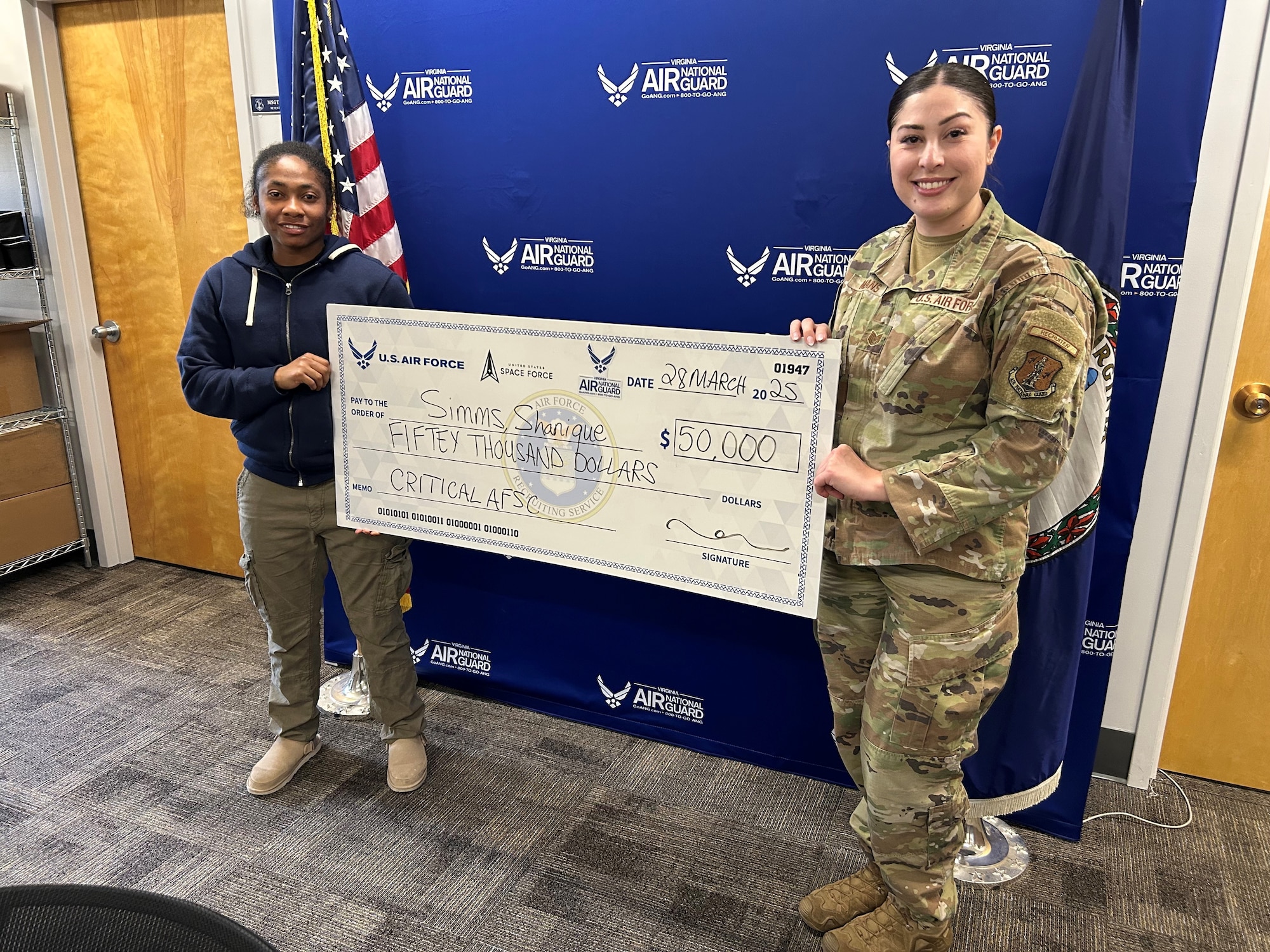 Tech. Sgt. Raychelle Means, right, presents a signing bonus check to a new Virginia Air National Guard recruit.