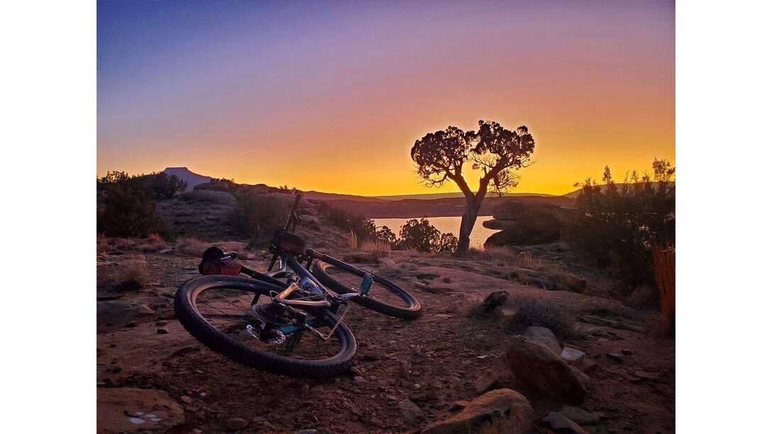 A mountain bike rests in the foreground on the mountain biking and hiking trail as the sun sets over Abiquiu Lake, N.M., Feb. 5, 2025. Photo by Samantha Jones, operations project manager, Rio Grande Basin.