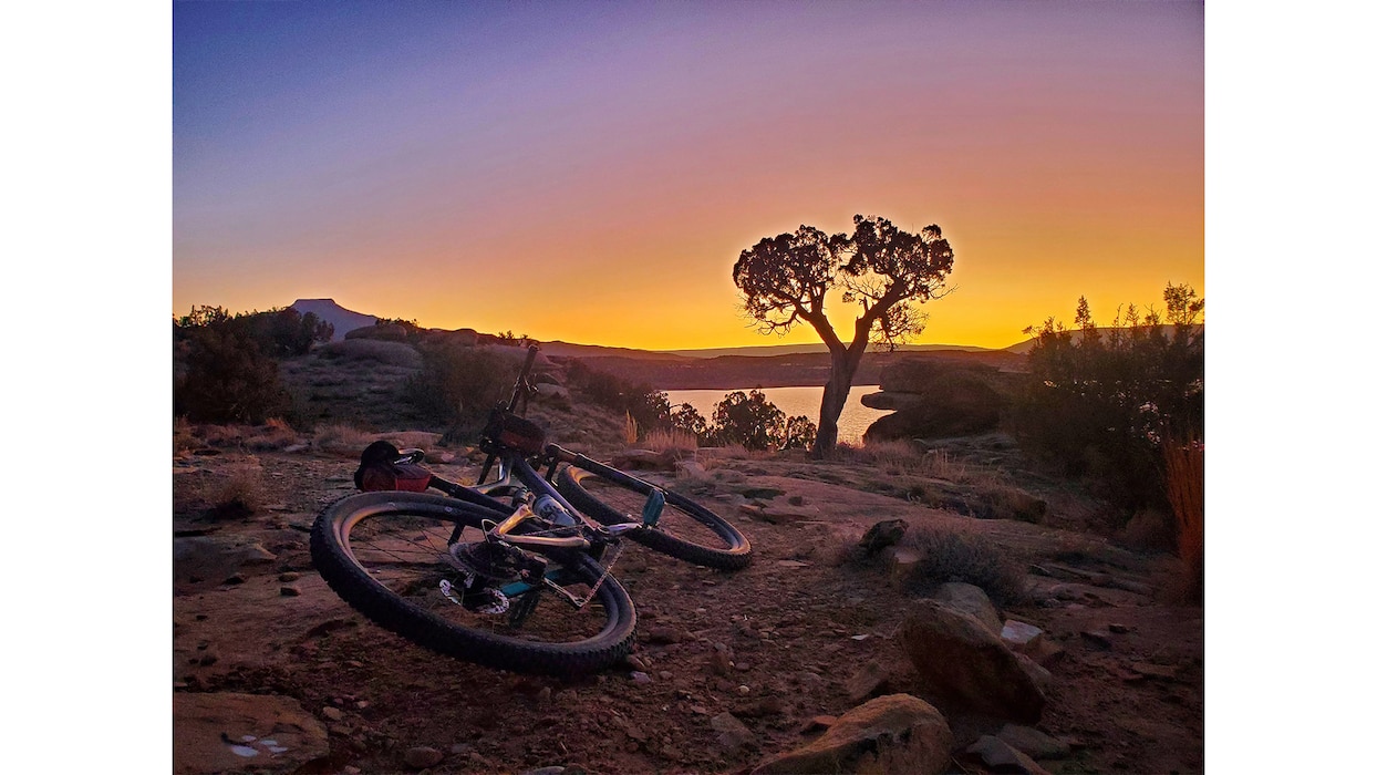 A mountain bike rests in the foreground on the mountain biking and hiking trail as the sun sets over Abiquiu Lake, N.M., Feb. 5, 2025. Photo by Samantha Jones, operations project manager, Rio Grande Basin.