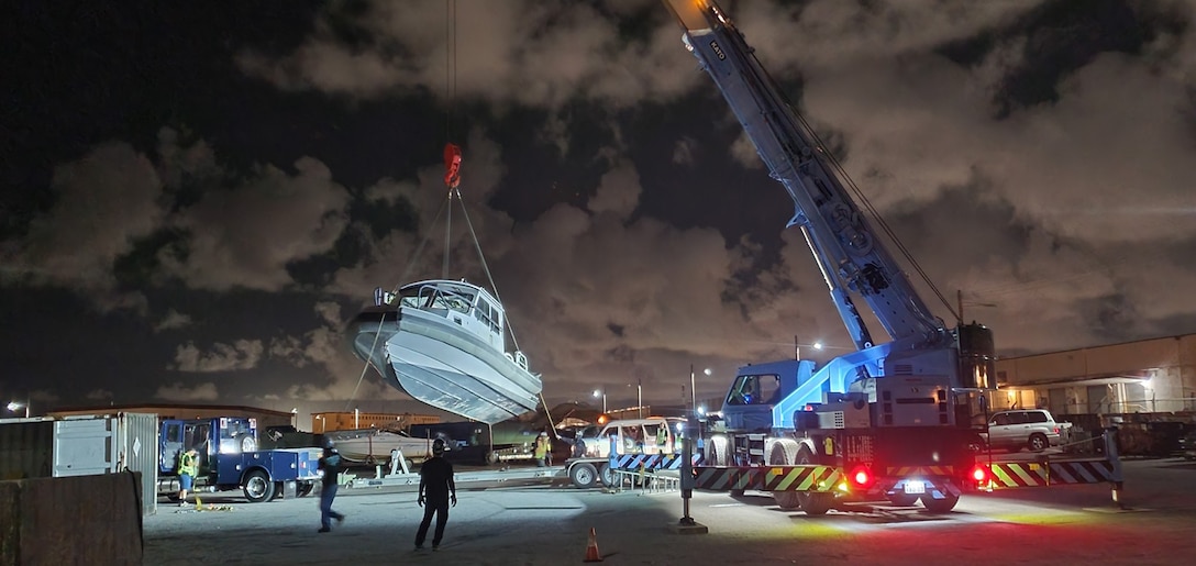A large crane lifts a boat at night.