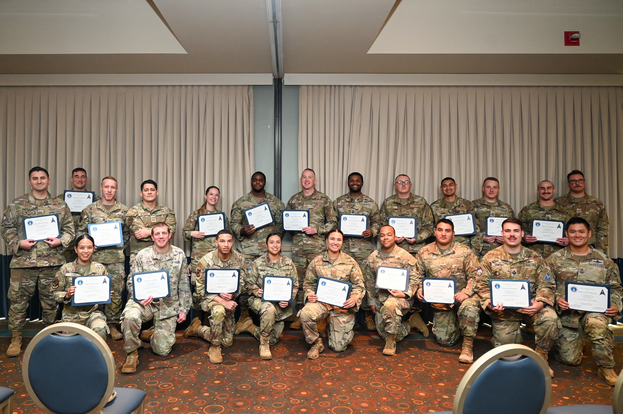 Vandenberg First Sergeant graduates kneel in the front and stand in the back for a team photo after the First Sergeant Symposium at Vandenberg Space Force Base.
