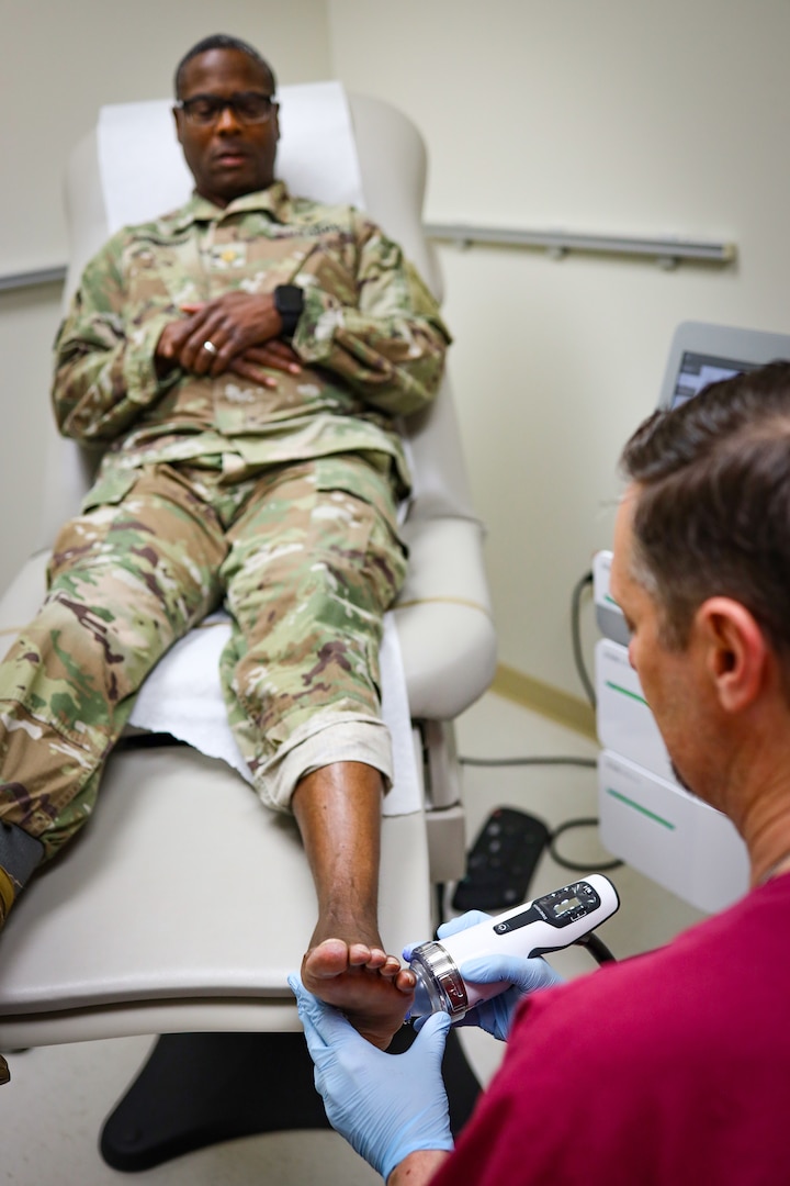 A podiatrist at Irwin Army Community Hospital applies 2,500 low-intensity soundwave pulses designed to stimulate blood flow, reduce inflammation, and encourage bone regeneration to a patient who suffered a fifth metatarsal avulsion fracture, a painful injury caused when a ligament pulled part of the bone away after he stepped into a pothole during a run.