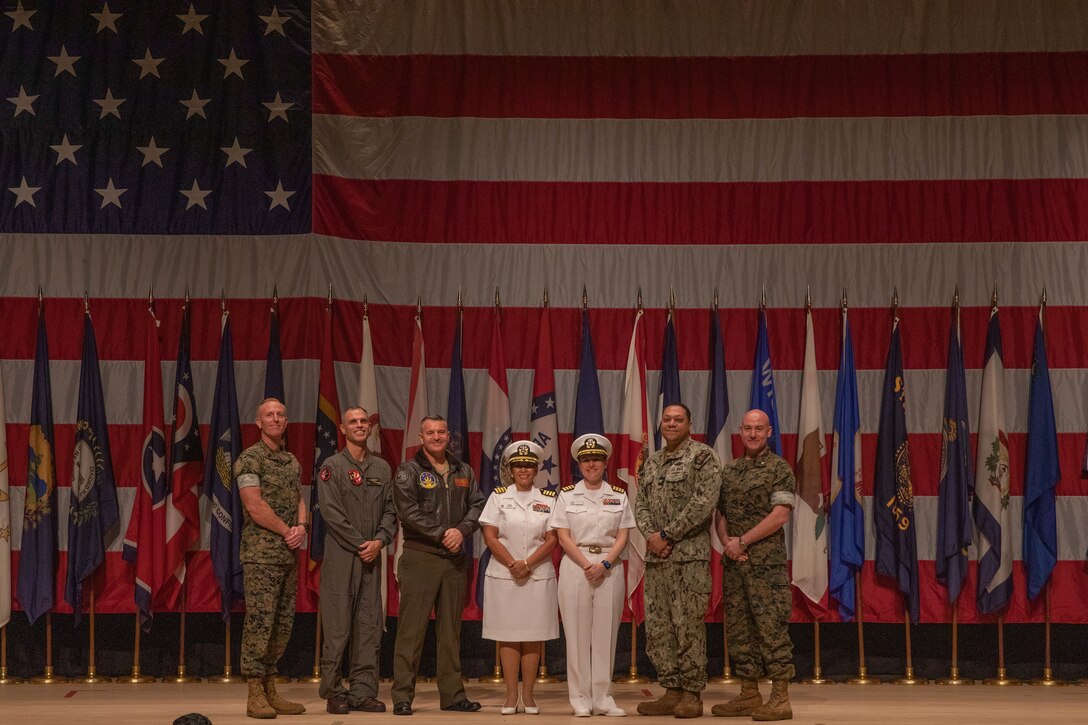 Leadership from Headquarters and Headquarters Squadron (HHS), Marine Corps Air Station Iwakuni, Navy Medical Readiness Training Unit Iwakuni, and NMRTU Okinawa, pose for a photo during the promotion ceremony of U.S. Navy Capt. Jacqueline Lopez, officer in charge, Navy Medicine Readiness and Training Unit Iwakuni at Marine Corps Air Station Iwakuni, Japan, Oct. 3, 2025. Naval Family Branch Clinic Iwakuni has the critical role of providing MCAS Iwakuni personnel and their families with healthcare services and helping to ensure medical readiness throughout the Indo-Pacific. (U.S. Marine Corps photo by Lance Cpl. Tyler Bassett)