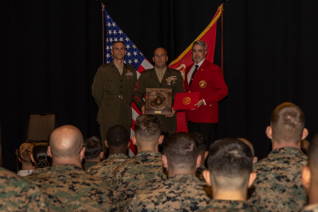 U.S. Marine Corps Lt. Col. Federico Mendizabal, left, the commanding officer of Headquarters and Headquarters Squadron (HHS), Marine Corps Air Station Iwakuni, and a New York native, award recipient Gunnery Sgt. Robert Navarro, center, the officer in charge of the indoor small arms range with HHS, MCAS Iwakuni, and a native of Oceanside, California, and Rob Brooks, national director of events for the Marine Corps League, pose for a picture during the Gunnery Sgt. Carlos N. Hathcock II award ceremony at MCAS Iwakuni, Japan, Nov. 4, 2025. Gunnery Sgt. Navarro was awarded the Gunnery Sgt, Carlos N. Hathcock II award for his prestigious work and dedication to improving marksmanship of the ISAR and efficiently training rifle and pistol qualifications. (U.S. Marine Corps photo by Lance Cpl. Isaac De Leon)
