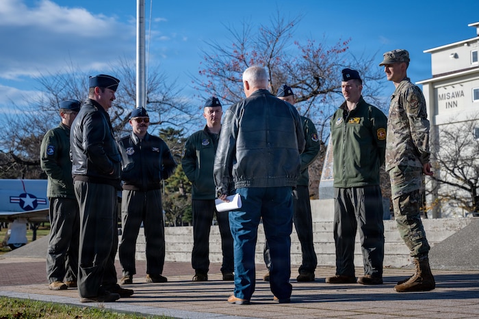 Retired U.S. Air Force Lt. Col. William “Mother” Forkner, center in civilian attire, Air Education and Training Command chief of combat air forces training branch, reads his speech on remembering Capt. Warren “Reefer” Sneed, former 14th Fighter Squadron assistant weapons officer, during a Veterans Day remembrance ceremony.