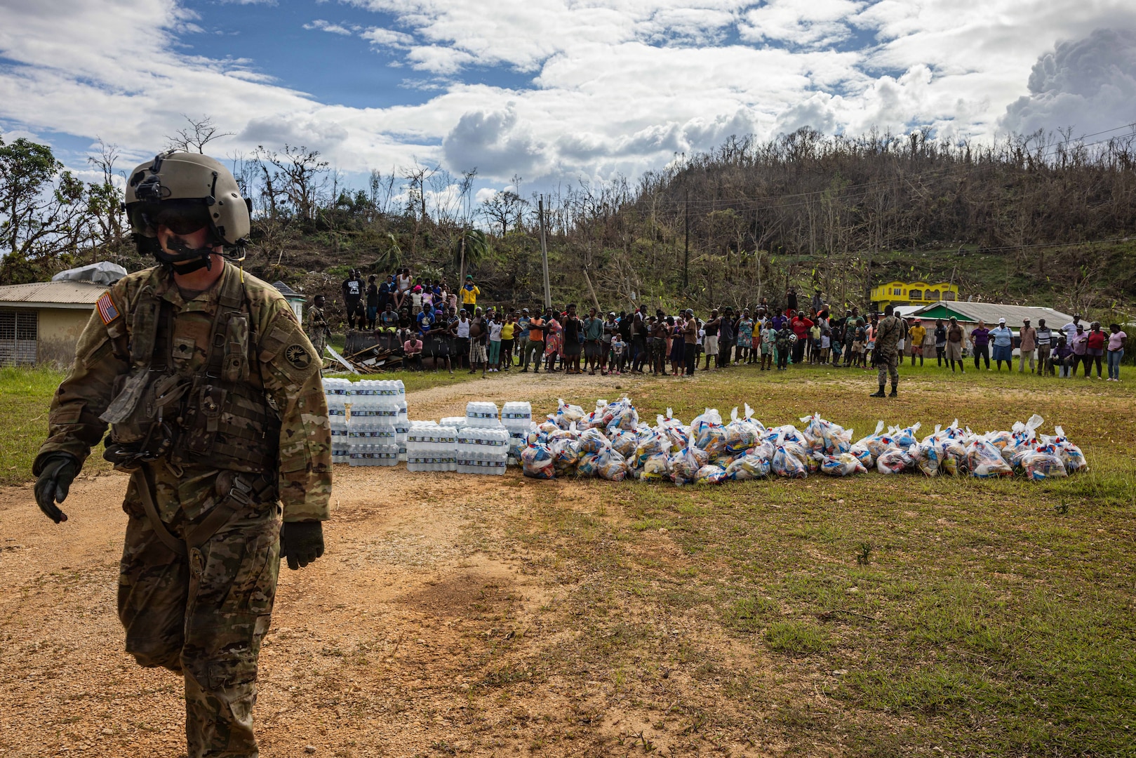 A military man walks in front of supplies on the ground