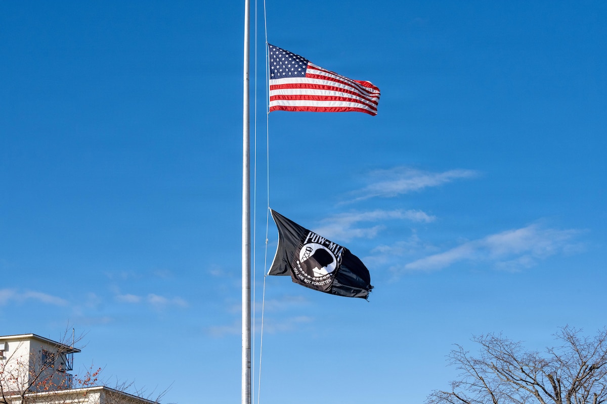 A U.S. and  POW/MIA flag fly in the wind during a Veterans Day remembrance ceremony.
