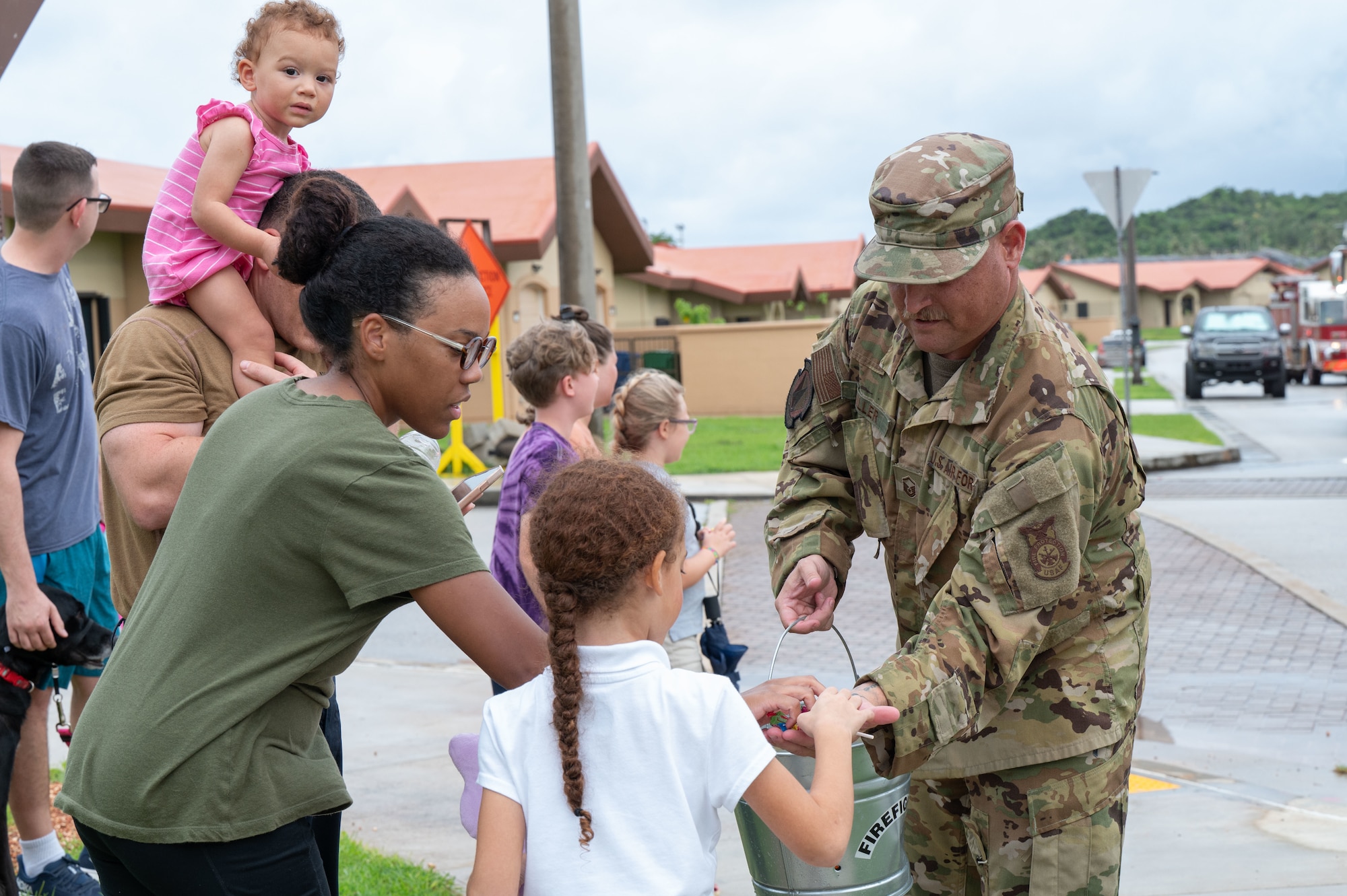 U.S. Air Force Master Sgt. Justin Miller, right, the assistant chief of fire prevention for the 36th Civil Engineer Squadron Fire Department, hands out candy to attendees during the 2025 Fire Prevention Week Housing Parade at Andersen Air Force Base, Guam, Oct. 7, 2025.