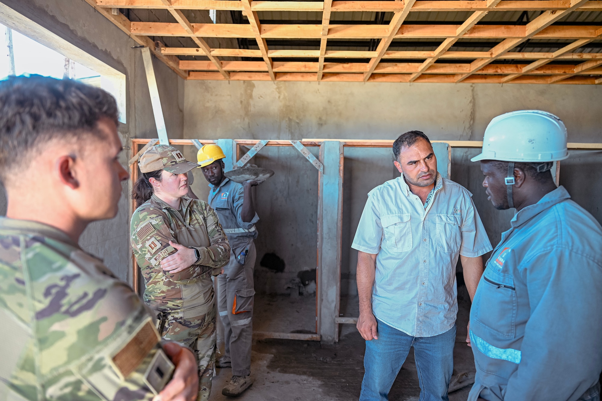 U.S. Airmen from the 475th Expeditionary Air Base Squadron discuss construction progress with a Kenyan construction worker during an infrastructure improvement project at Camp Simba, Kenya, Oct. 22, 2025.
