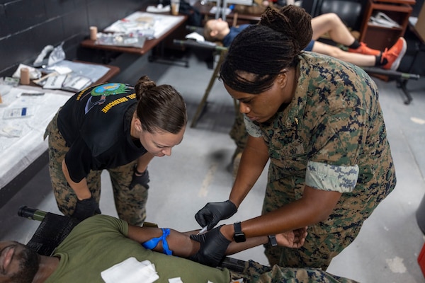 U.S. Navy Hospital Corpsman 2nd Class Sarah Kunkle, left, a Tier IV Tactical Casualty Combat Care course instructor, watches over LT. Calithea Sheppard, a medical officer with 2nd Medical Battalion, 2nd Marine Logistics Group, while practicing drawing blood during a Tier IV Tactical Casualty Combat Care course at Marine Corps Base Camp Lejeune, North Carolina, Sept. 29, 2025. 2nd MLG became the first-ever Marine Corps command to host a Tier IV TCCC course and is now hosting its second iteration. The course trains select military service members to become proficient combat paramedics capable of providing advanced casualty care at the point of injury on the battlefield and in austere environments. (U.S. Marine Corps photo by Lance Cpl. Isabella Ramos)