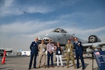 U.S. Air Force Lt. Gen. Derek France, Air Forces Central commander, stands with service members and Department of War civilians in front of an A-10 Thunderbolt aircraft while a B-52 Stratofortress aircraft flies in the background at the Al Maktoum International Airport, Dubai, Nov. 17, 2025. They attended the Dubai International Airshow, an event that strengthens ties between U.S. forces and international partners in aviation and national defense. (U.S. Air Force photo by Tech. Sgt. Justin Norton)
