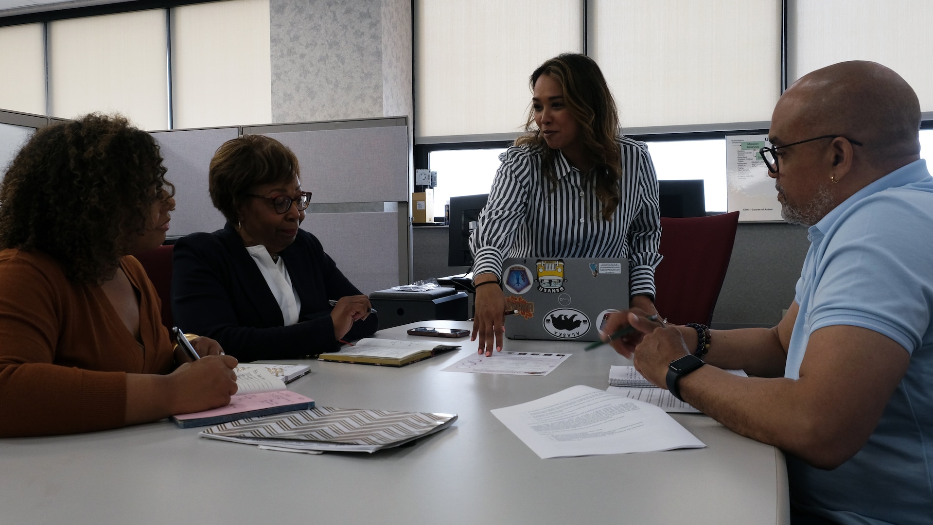 Miranda Cook, Sylvia Morris, Lety Flores and Oliver Brown collaborate on upcoming Transformation Surge Team  projects during a team meeting. The TST launched PEAK, USMEPCOM's new HR system, on Nov. 12, 2025.