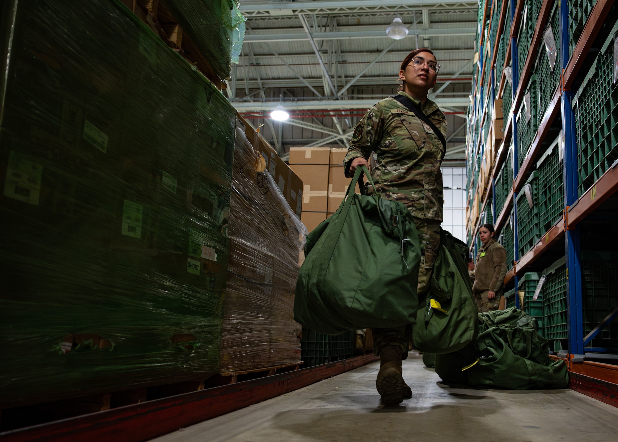 U.S. Air Force Staff Sgt. Ariel George, 100th Aircraft Maintenance Squadron crew chief, walks down a simulated personnel deployment function line at RAF Mildenhall, England, Oct. 29, 2025. The 100th Air Refueling Wing participated in Exercise King Bee, showcasing the abilities of its airmen in implementing contingency operations. (U.S. Air Force photo by Airman 1st Class Aidan Martínez Rosiere)