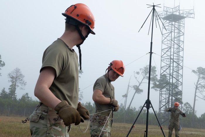 Three airmen are assembling an antenna