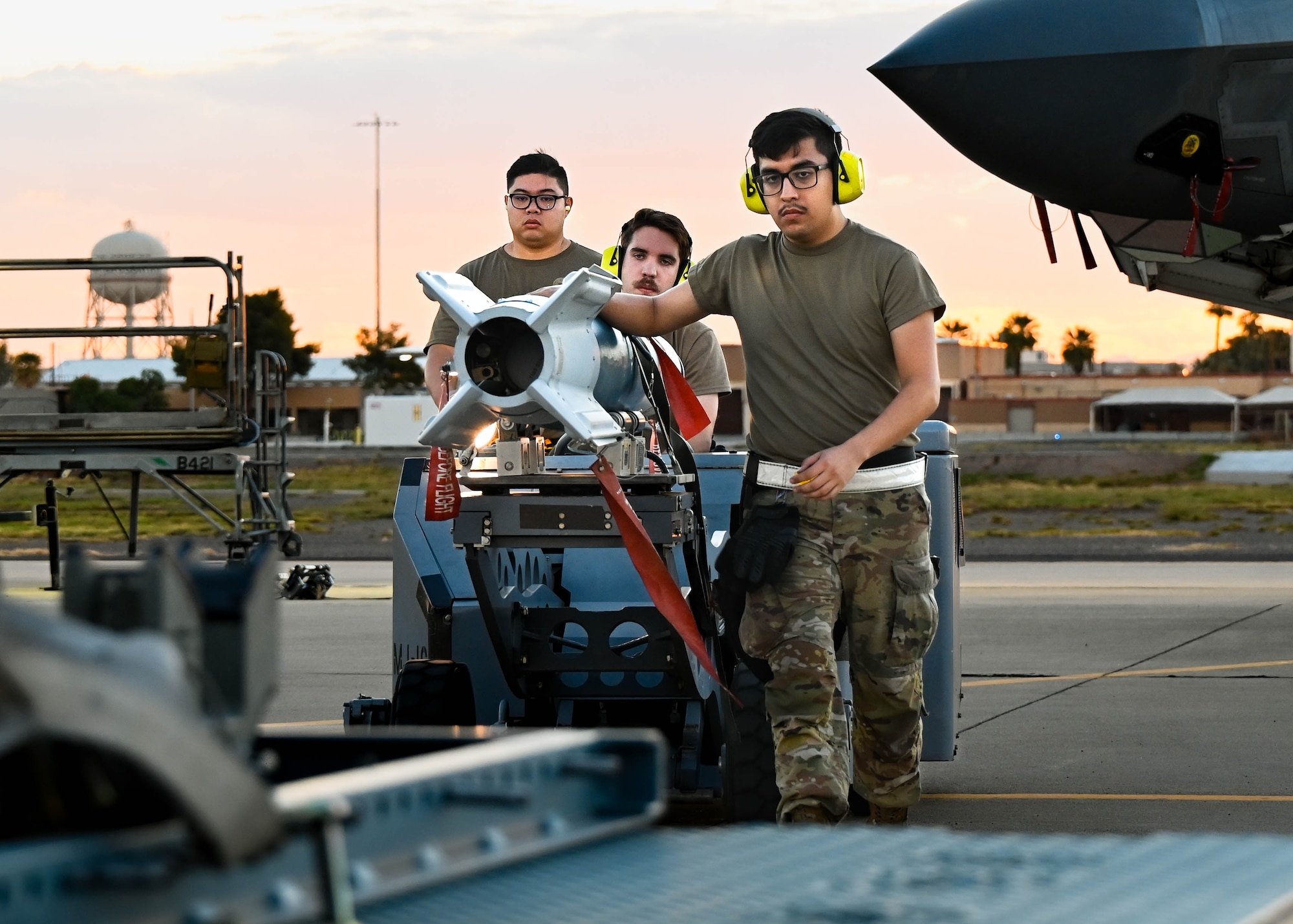 U.S. Air Force Staff Sgt. Khaim Vongjalorn (left), Senior Airman Titan Henley (middle), Airman 1st Class Leonardo Noyola (right), 61st Aircraft Maintenance Unit aircraft armament systems specialists, transport a GBU-12 bomb with an MJ-1 bomb lift truck during a Phase 2 Aircraft Generation exercise