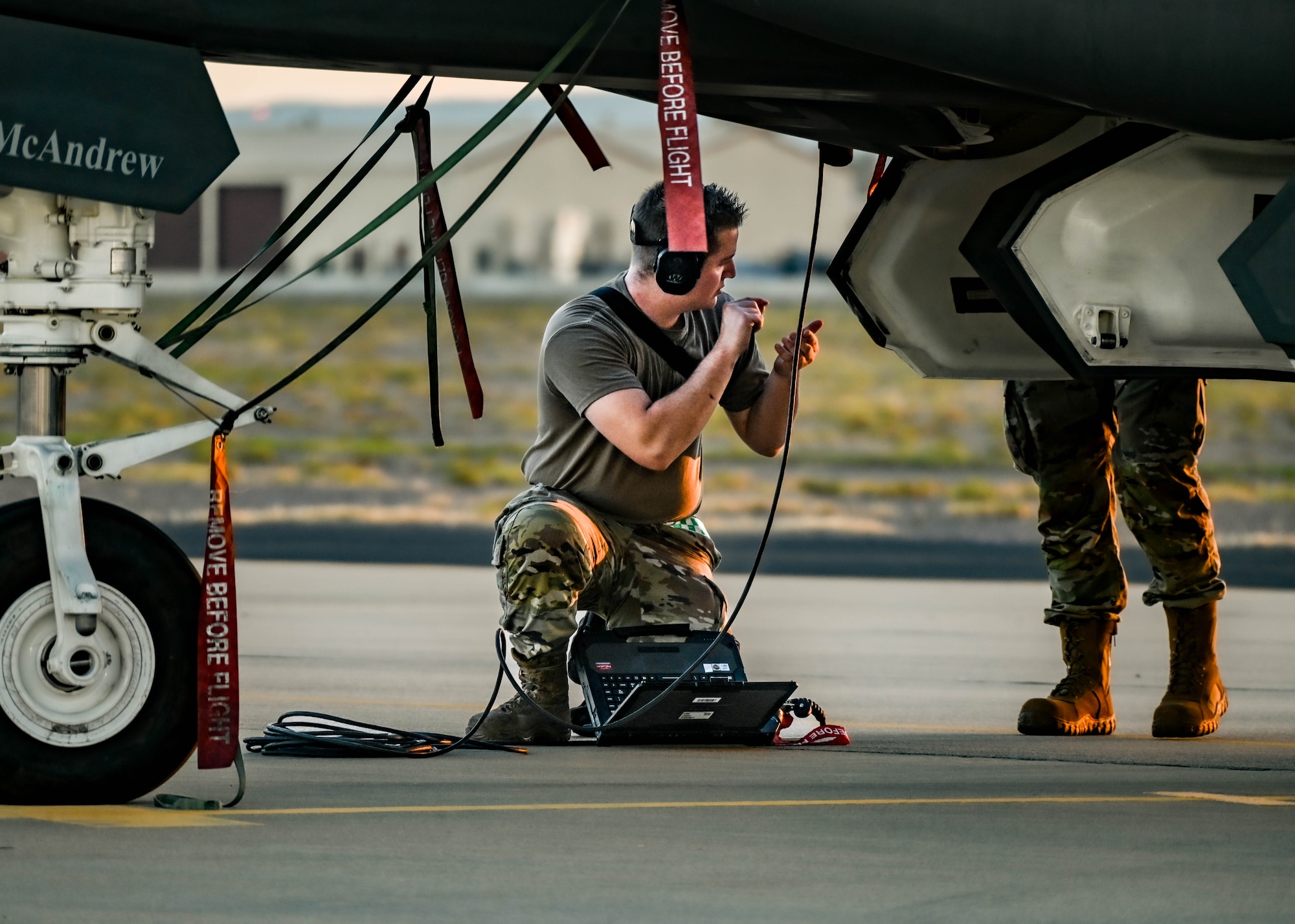 U.S. Air Force Staff Sgt. Ryan Fields, 308th Aircraft Maintenance Unit F-35A Lightning II integrated avionics specialist, kneels under the fuselage and uses a specialized system to ready a jet for flight during a Phase 2 Aircraft Generation exercise