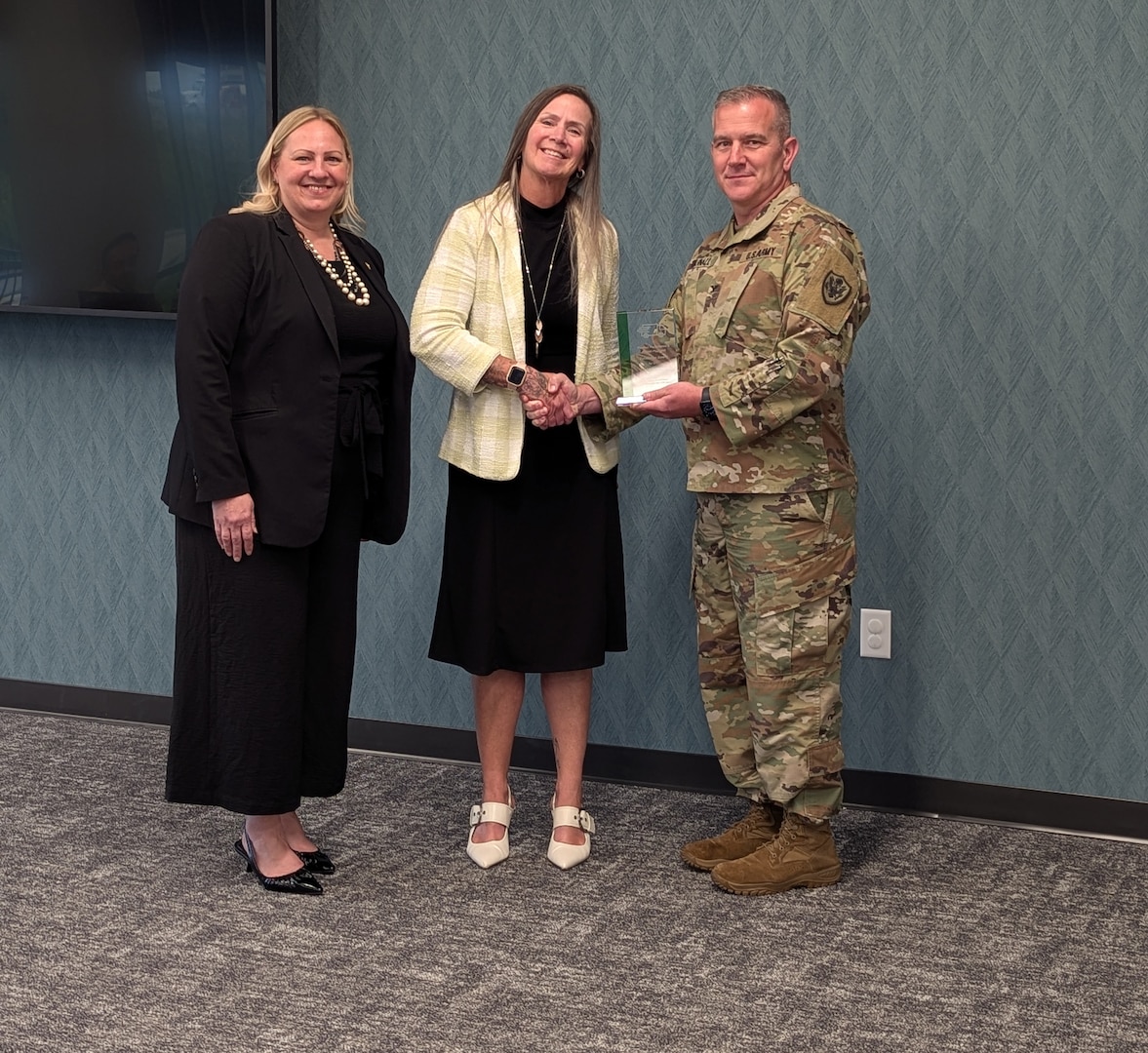 Two women and a man wearing a military uniform pose for a picture