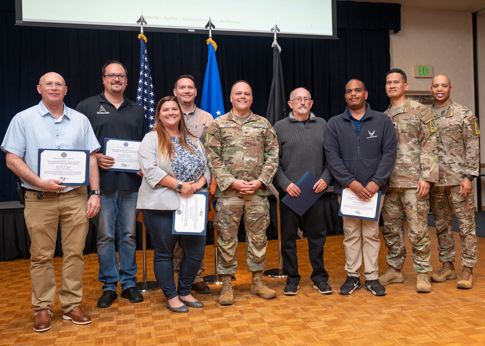 U.S. Space Force Col. James Horne III, Space Launch Delta 30 commander and Chief Master Sgt. Malcolm Summers, SLD 30 senior enlisted airman, stand with Team Vandenberg members. The members are holding certificates of special recognition.