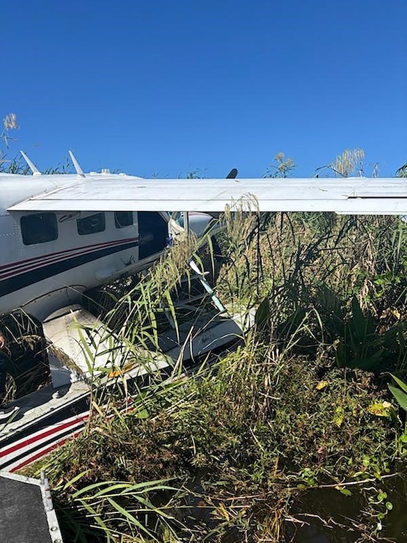 A small, private sea plane rests amid brush on the edge of Lake Okeechobee after crash landing. All three personnel on board were safe.