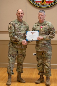 U.S. Air Force Brig. Gen. Matthew McDonough, commander of the 113th Air Wing, District of Columbia Air National Guard, left, presents the Legion of Merit medal to Chief Master Sgt. Sean. M. Larson during a change of responsibility ceremony transitioning the D.C. Command Chief Master Sgt. at the D.C. Armory in Washington, Nov. 9, 2025. Larson enlisted in the Air Force in 1986 and has held multiple high-profile assignments in active duty component, Iowa Air National Guard, and the D.C. Air National Guard.
