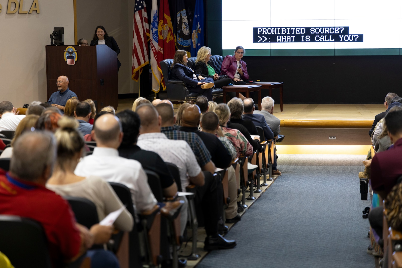 The contestants on stage laugh during a mock Jeopardy game.