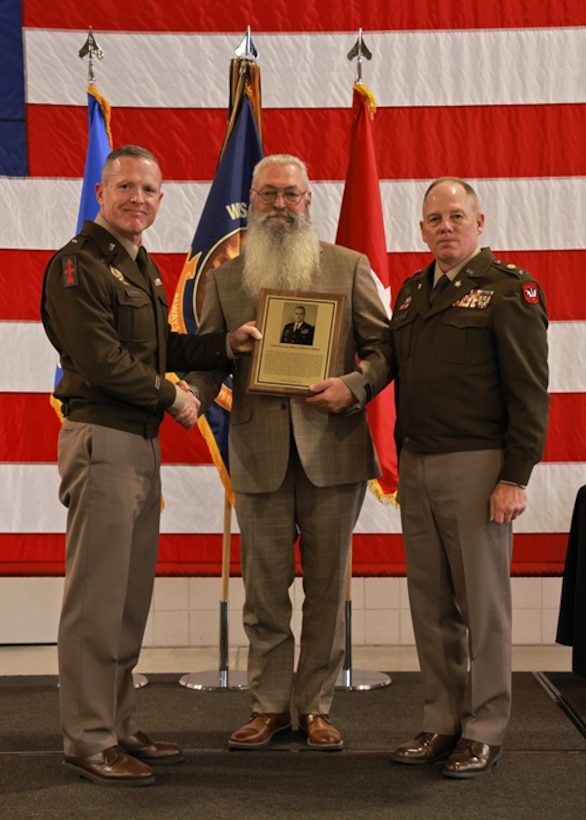 U.S. Army Brig. Gen. Brion Aderman, Wisconsin’s deputy adjutant general for Army, left, and Command Sgt. Maj. Duane Weyer, the state’s command sergeant major, present retired Chief Warrant Officer 4 David Molitor his Hall of Honor plaque during the 2025 Wisconsin Army National Guard Hall of Honor Induction Ceremony at the Department of Military Affairs facility in Madison, Wisconsin, Nov. 1, 2025. The Hall of Honor program was established in 2000 to recognize Wisconsin National Guard Soldiers who have distinguished themselves through exceptional achievement and devotion to duty, significantly contributing to the enduring legacy of the organization. (U.S. National Guard photo by Paul Gorman)