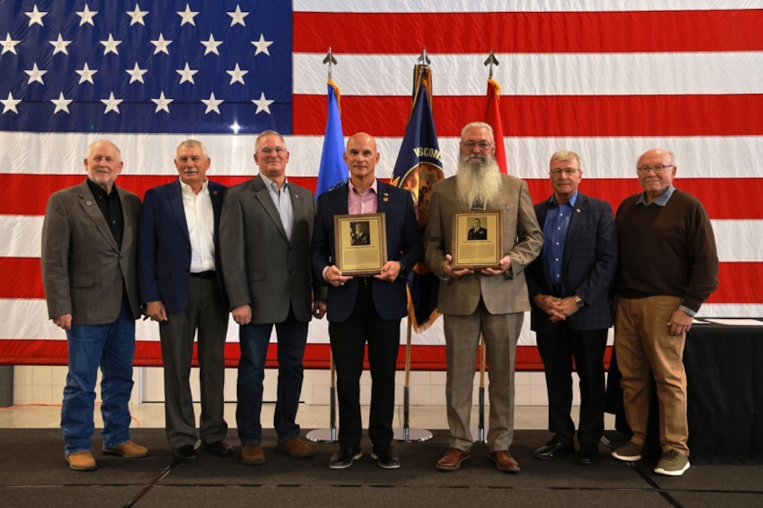 Retired U.S. Army Command Sgt. Maj. Rafael Conde and retired U.S. Army Chief Warrant Officer 4 David Molitor are joined by prior Wisconsin Army National Guard Hall of Honor recipients following their induction ceremony at the Department of Military Affairs facility in Madison, Wisconsin, Nov. 1, 2025. The Hall of Honor program was established in 2000 to recognize Wisconsin National Guard Soldiers who have distinguished themselves through exceptional achievement and devotion to duty, significantly contributing to the enduring legacy of the organization. (U.S. National Guard photo by Paul Gorman)