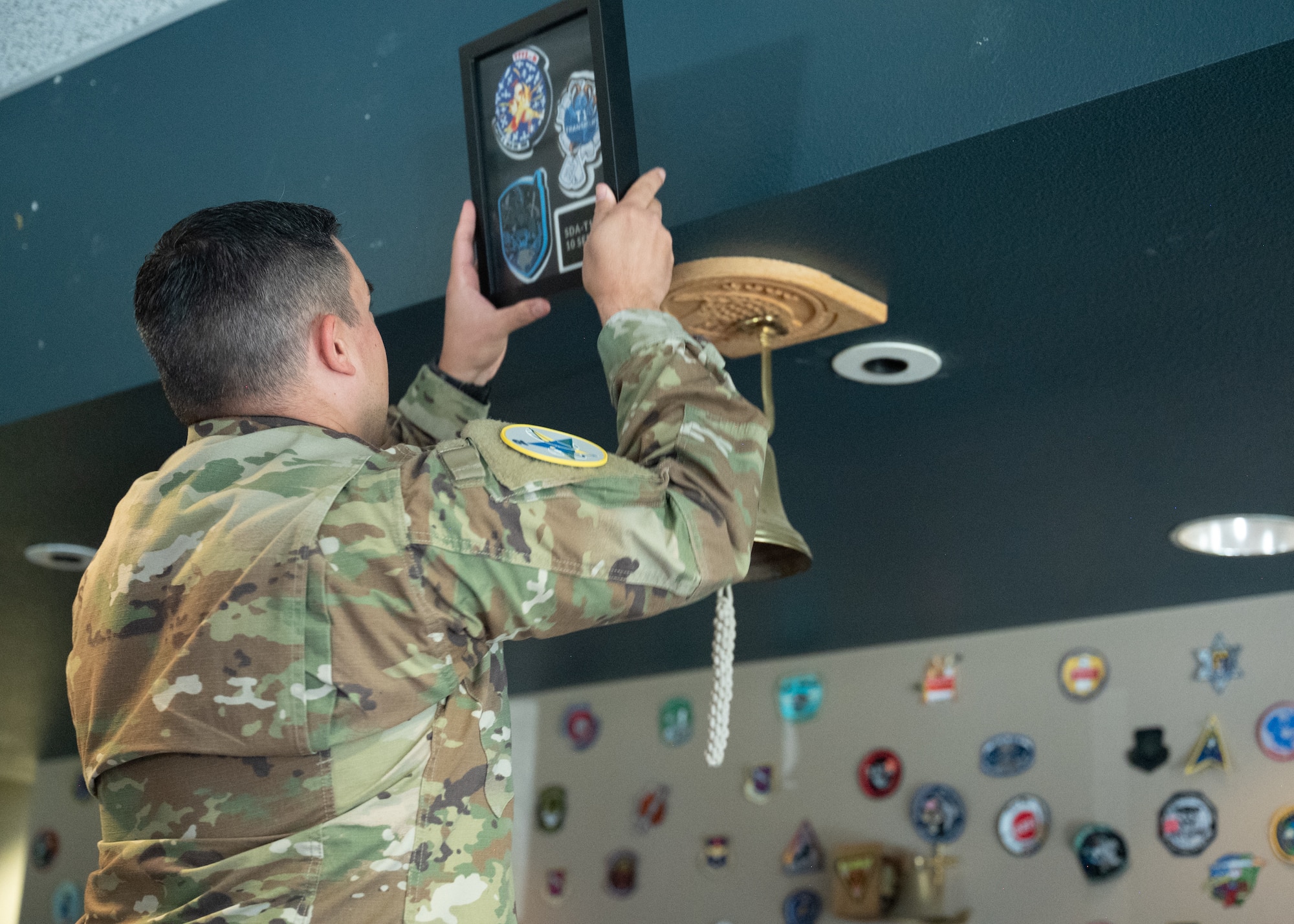 Lt. Col. Ralph Salazar, 2nd Range Operations Squadron commander, stands and hangs a frame on the wall.